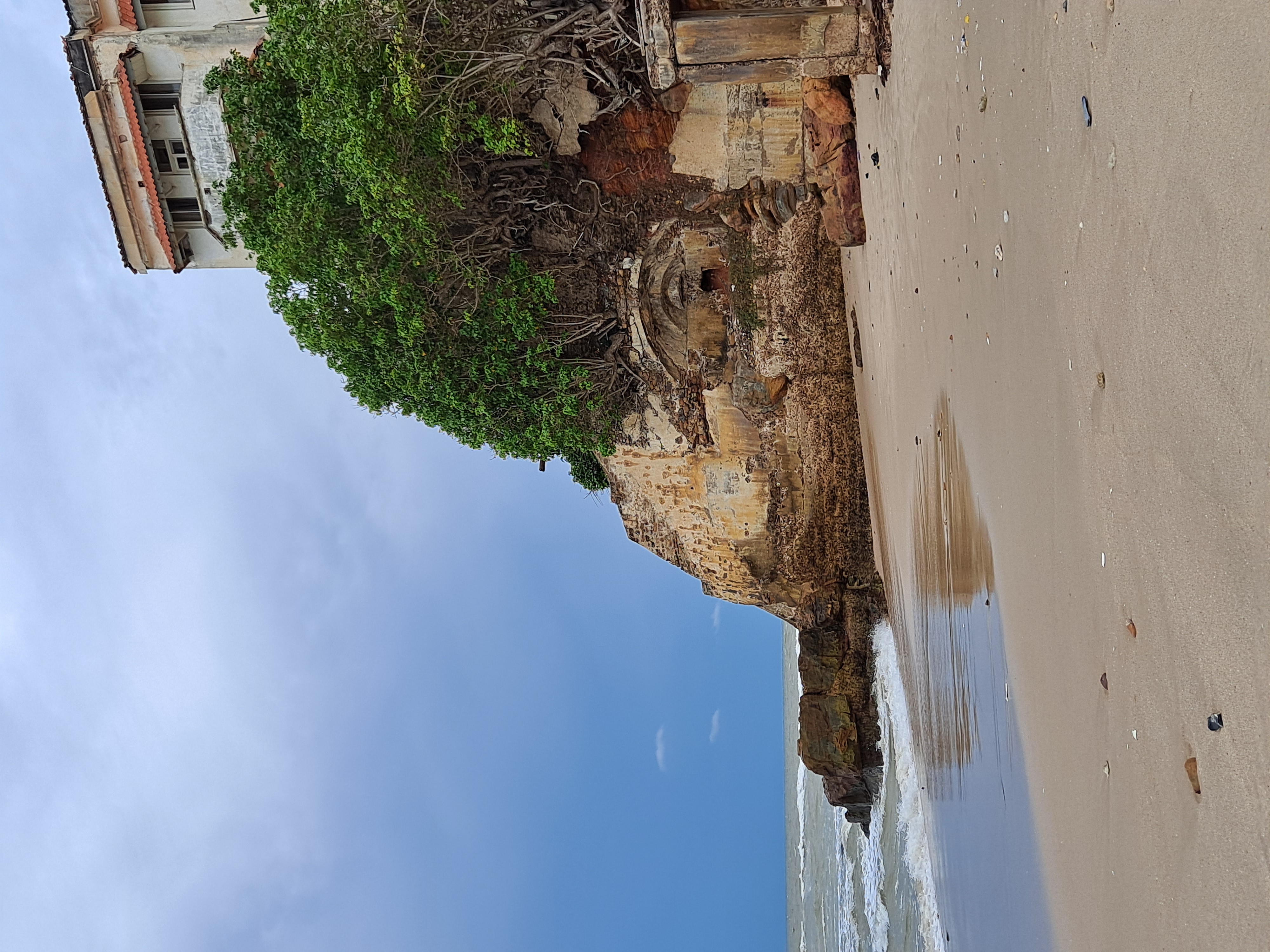 A picture of the beach and the natural rock foundations with Osu Castle rising above under a gloomy sky.